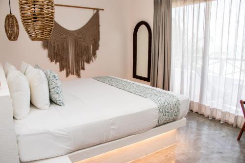 a white bed in a room with a window at HAU Holbox, Oceanfront Boutique Hotel in Holbox Island