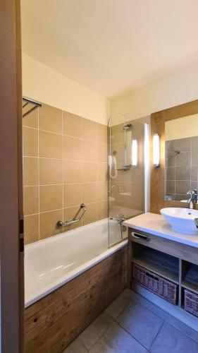 une salle de bain avec une baignoire et un lavabo dans l'établissement Résidence Les Terrasses D'eos - Appartement spacieux · Accès direct aux pistes · Piscine · WIFI gratuit et illimité · Spa MAE-1661, à Magland