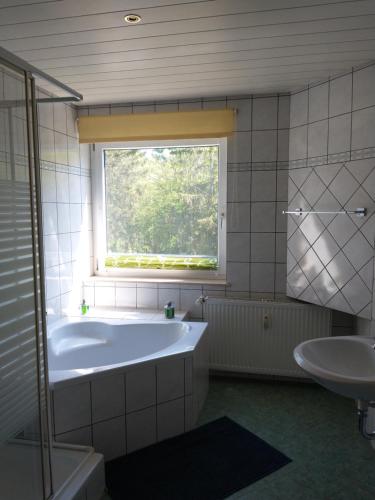 a bathroom with a tub and a sink and a window at Immensee in Ronshausen