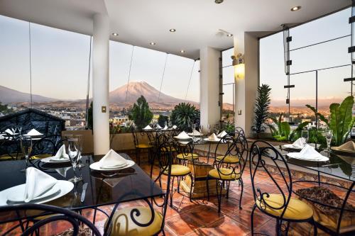 a restaurant with tables and chairs and mountains in the background at Natura Inn Hotel in Arequipa