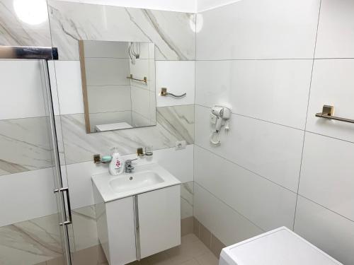 La salle de bains blanche est pourvue d'un lavabo et d'un miroir. dans l'établissement Fishta Apartment Q6 37, à Velipojë