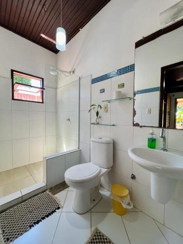a white bathroom with a toilet and a sink at Tropical Hostel in Pipa