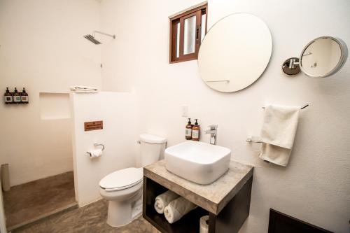 a white bathroom with a sink and a mirror at HAU Holbox, Oceanfront Boutique Hotel in Holbox Island