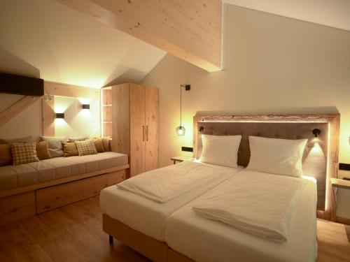 a bedroom with a large white bed and a couch at Hotel Bütgenbacher Hof in Butgenbach