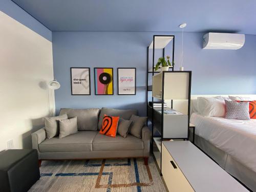 1 dormitorio con sofá, cama y paredes azules en Morcelli Mobiliados - Uniqo Smart Living, en Santa Maria