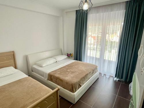 a bedroom with two beds and a window with green curtains at Fishta Apartment Q6 37 in Velipojë