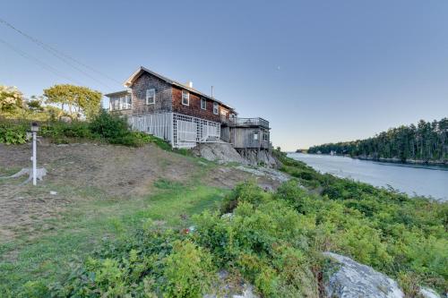 an old house on a hill next to a river at Oceanfront Cottage with Deck 2 Mi to Boothbay Harbor in West Boothbay Harbor