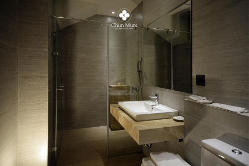 een badkamer met een wastafel en een douche met een spiegel bij Chun Mure Hotel in Dahan