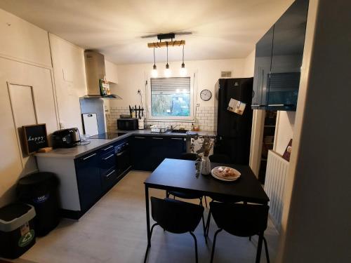 une petite cuisine avec une table et un réfrigérateur noir. dans l'établissement Cosy appartement près *RER et Disney, Paris, à Villiers-sur-Marne