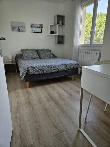 une chambre avec un lit et un parquet dans l'établissement Le Triolet, à Sète