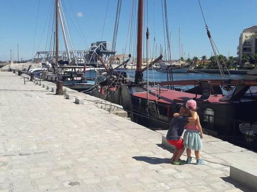 un homme et une femme debout sur un quai avec des bateaux dans l'établissement Le Triolet, à Sète