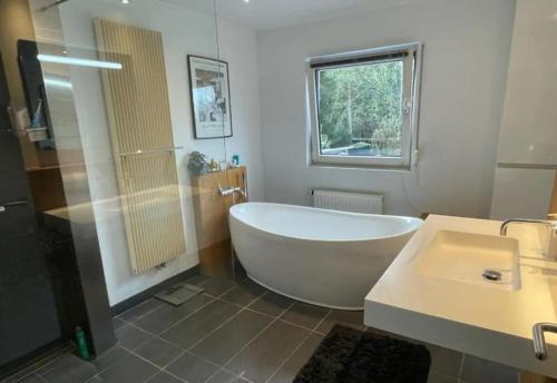 a bathroom with a tub and a sink at Nice house with swimming pool near Maastricht in Bunde