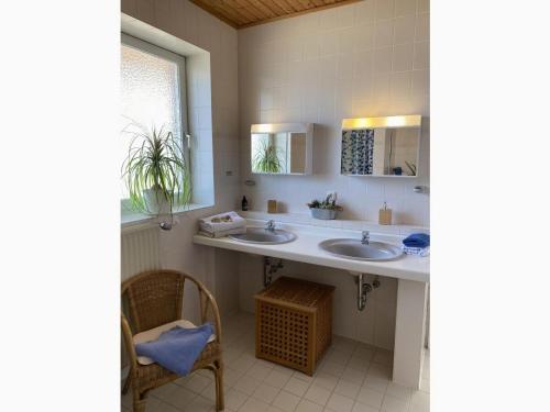 a bathroom with two sinks and a chair at Holiday apartment 2 in the Maaßen country house in Stakendorf