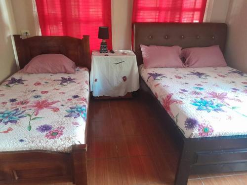 a bedroom with two beds and a table with a lamp at Cabaña el Tecal in San Francisco
