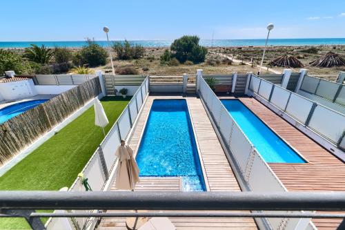 ein Schwimmbad mit Strand im Hintergrund in der Unterkunft Casa frente al mar con piscina privada in Sagunt