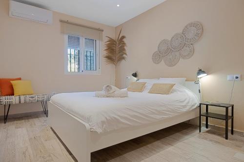 a white bedroom with a large white bed and a window at Casa Pitaya in Alhaurín el Grande