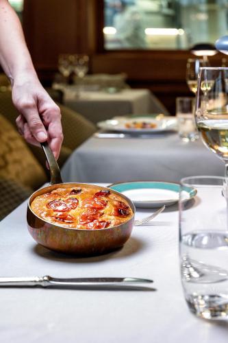 a person is holding a spoon in a dish on a table at Baglioni Hotel Luna - The Leading Hotels of the World in Venice