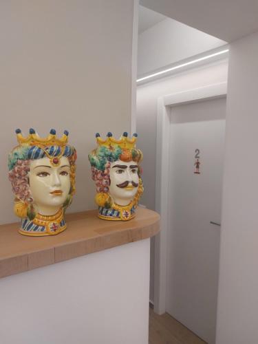 two statues of heads on a shelf in a room at GiglioApartment Etna Mare in Aci Castello