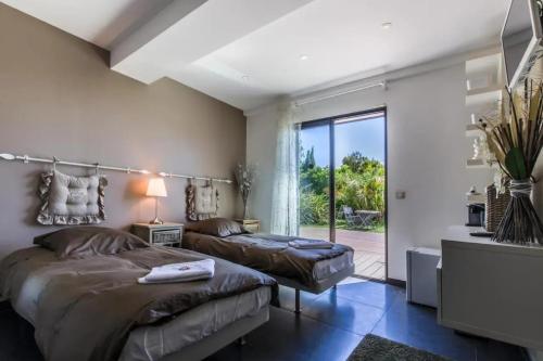 une chambre avec deux lits et un balcon dans l'établissement Villa Luxueuse à Cavalaire-sur-Mer, à Cavalaire-sur-Mer