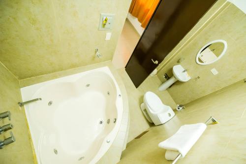 y baño con bañera, aseo y espejo. en Hotel Luxor Pucallpa en Pucallpa