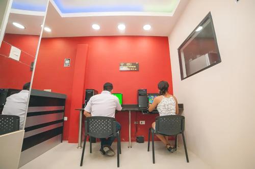 Un uomo e una donna seduti a una scrivania con un computer di Hotel Luxor Pucallpa a Pucallpa