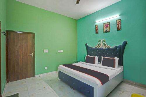 a bedroom with a king sized bed with green walls at OYO Omi Guest House in Gurgaon