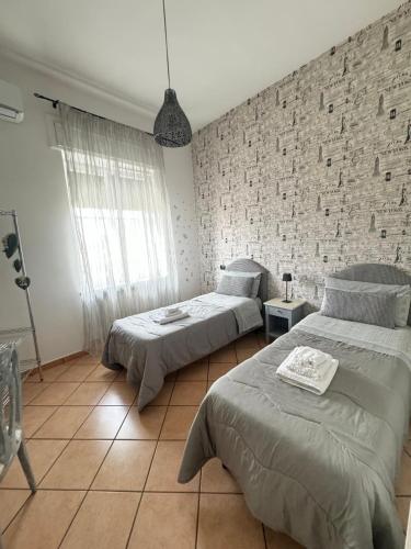 a bedroom with two beds and a brick wall at Tommy's Apartment in Pompei