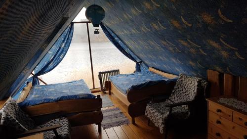 a room with a tent with two beds and a chair at Oreivių užuovėja in Keymintse