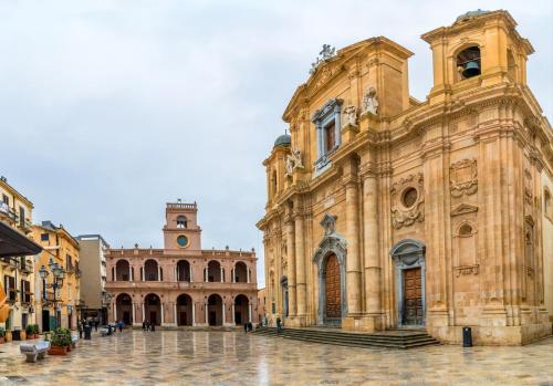 an old building with a clock tower in a courtyard at Appartamento Rosso Marsala in Marsala