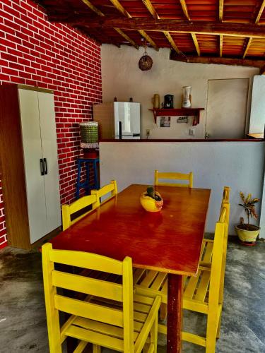 a dining room table with yellow chairs around it at Pousada flor do sertão in Piranhas