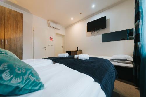 a bedroom with a large white bed with a tv on the wall at Old Town Residence Rooms in Sarajevo