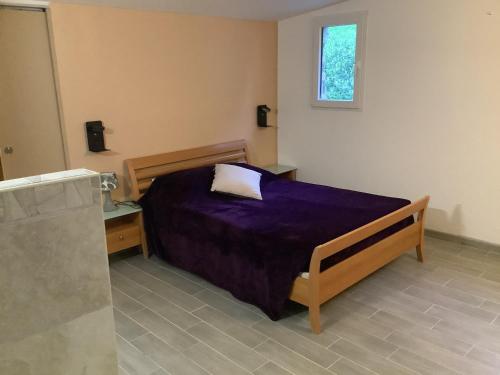 - une chambre avec un lit doté de draps violets et une fenêtre dans l'établissement Gîte de la vallée, à Siorac-en-Périgord
