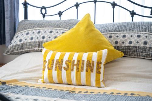 a yellow pillow sitting on a bed with pillows at Golf Links Cottage - Views of Royal County Down in Newcastle