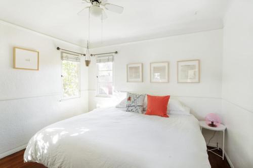 Dormitorio blanco con cama blanca y almohadas rojas en Silver Lake Mid-century Nestled In The Treetops en Los Ángeles