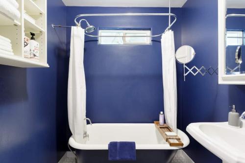 ein blaues Badezimmer mit einer Badewanne und einem Waschbecken in der Unterkunft Silver Lake Mid-century Nestled In The Treetops in Los Angeles