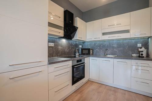 uma cozinha branca com armários brancos e um lavatório em KARINA APARTMAN em Dunajská Streda