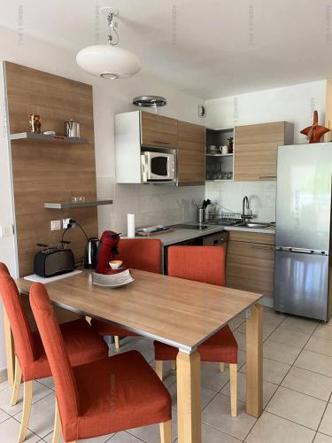 une cuisine avec une table en bois et des chaises rouges dans l'établissement Résidence Natureva - Appartement T2 2 PERS. MAE-2701, au Cap d'Agde