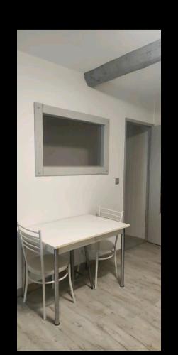 - une table et des chaises blanches dans la chambre dans l'établissement Maison de village avec son charme intérieur, à Nissan-lez-Enserune