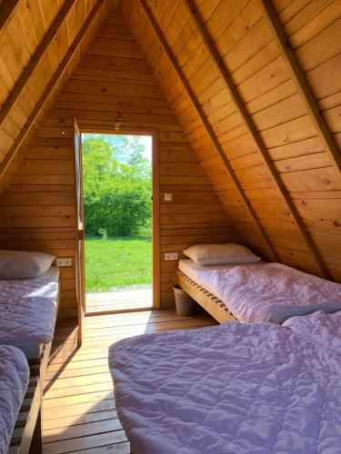 two beds in a wooden room with a window at Kuća za odmor KRNJAIĆ in Bosanski Novi
