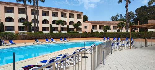 une piscine avec des chaises longues et un bâtiment dans l'établissement appartement bord de mer en Corse avec 2 piscines 100 metres de la plage, à Linguizzetta