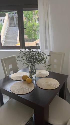 a black table with two plates and a vase with flowers at Apartments Arina in Krasici