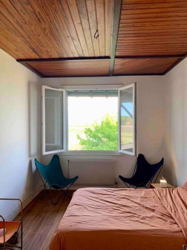 - une chambre avec deux chaises, un lit et une fenêtre dans l'établissement La maison Piclaouey, à Lège-Cap-Ferret
