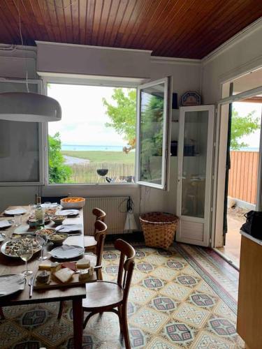 une salle à manger avec une table et des chaises et une grande fenêtre dans l'établissement La maison Piclaouey, à Lège-Cap-Ferret