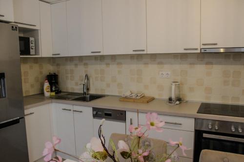 a kitchen with white cabinets and pink flowers at Villa Bali - Aladinici in Stolac