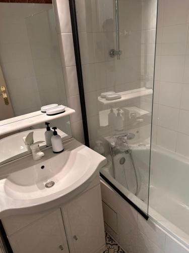 une salle de bain blanche avec un lavabo et une douche dans l'établissement Cosy chic, au Cap d'Agde
