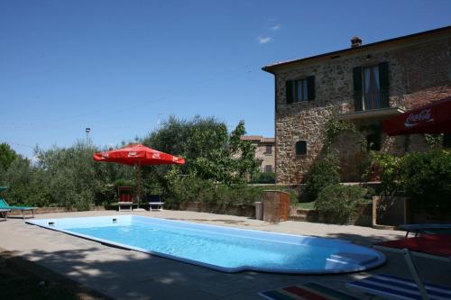 a swimming pool in front of a building with an umbrella at Casa Felice in Lucignano