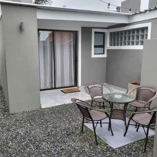 a patio with a glass table and chairs on a house at Willow Retreat Blouberg in Cape Town