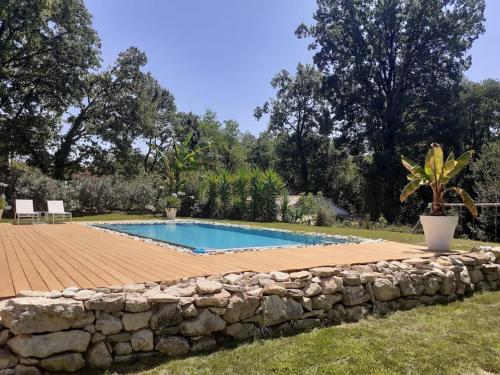 une piscine entourée d'un mur en pierre dans l'établissement Belle villa 10 pers dans le sud de la France, à Sommières