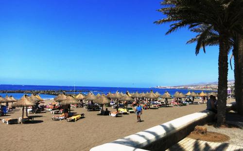 a beach with many umbrellas and people on the sand at BLUE BAY PARADISE - Beach front apartment with sea view in Playa Paraiso