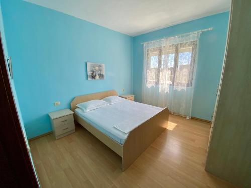 Schlafzimmer mit einem Bett mit blauen Wänden und Holzböden in der Unterkunft White & Blue Apartment's in Golem